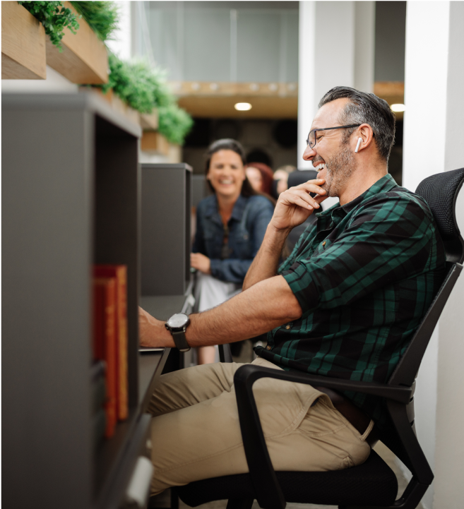 man at office desk looking at computer and laughing