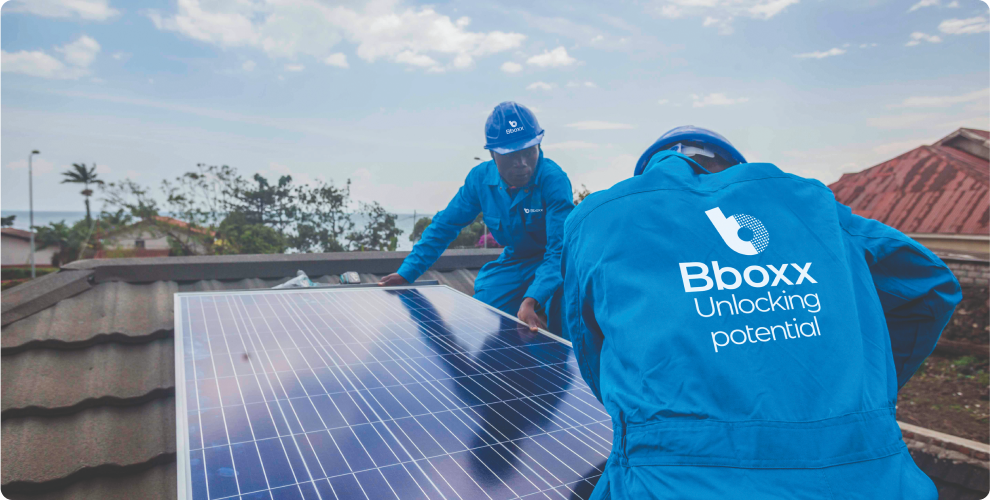 Two Engineers in PPE branded Bboxx working on solar panels